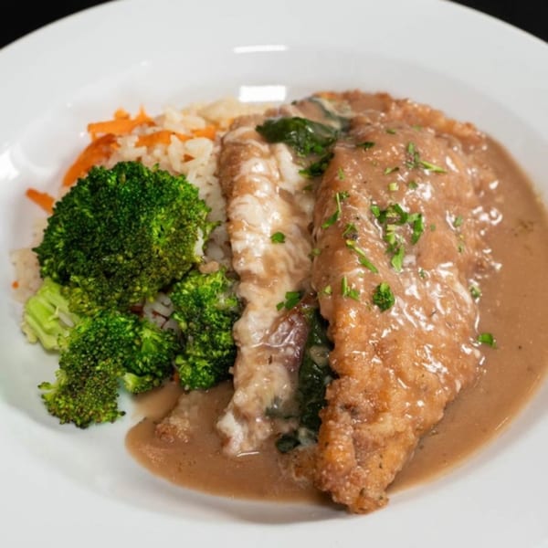 Giuseppe's chicken cutlet with gravy, rice, carrots, and broccoli on a white plate.
