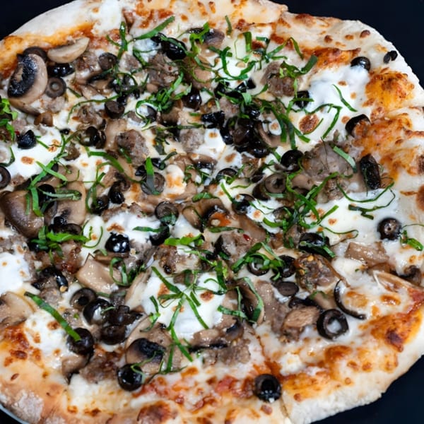 Giuseppe's Italian pizza with mushrooms, black olives, sausage, and fresh basil on a white sauce.