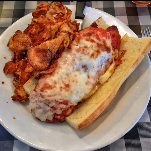 Giuseppe's chicken parmesan sandwich with melted cheese and red sauce, served with crispy chips.